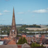 An elevated landscape view over the town centre of Rotherham, showing the rooftops with steeple and spire of the gothic Minster All Saints church