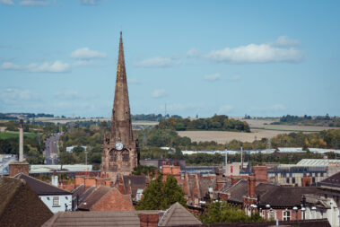 An elevated landscape view over the town centre of Rotherham, showing the rooftops with steeple and spire of the gothic Minster All Saints church