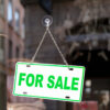 Close-up on an green sign in a window with written in it "For sale".