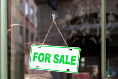Close-up on an green sign in a window with written in it "For sale".